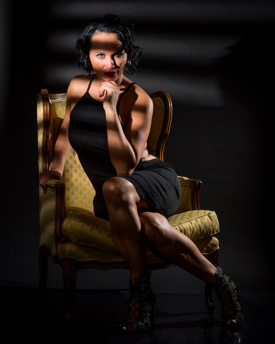 Woman posing on chair in half-light